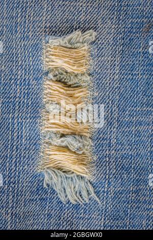 Blaue jean-Textur mit einem Loch und Fäden, die den Hintergrund zeigen Stockfoto