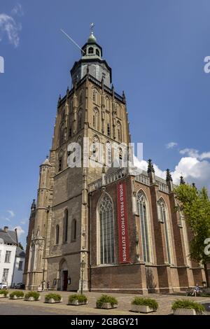 ZUTPHEN, NIEDERLANDE - 25. Jul 2021: Blauer Himmel hinter dem Turm der Walburgiskerk Kathedrale an einem sonnigen Tag mit großem roten Banner des World Press Photo Stockfoto