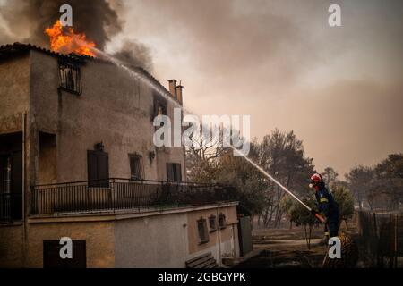 Varibobi, Griechenland. August 2021. Feuerwehrleute versuchen, die Flammen in einem brennenden Haus im Bezirk Varibobi im Norden Athens zu löschen. Quelle: Angelos Tzortzinis/DPA/Alamy Live News Stockfoto