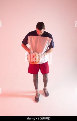 Europäischer Basketballspieler, der im Studio den Ball hält Stockfoto