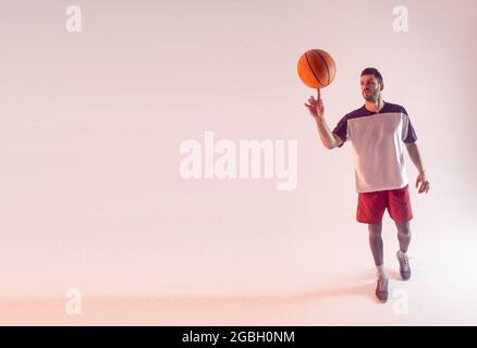 Der junge Sportler spinnt mit dem Finger einen Basketballball Stockfoto