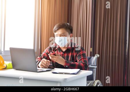 Architekt im Rollstuhl, der an einem Schreibtisch in einem Büro arbeitet Stockfoto