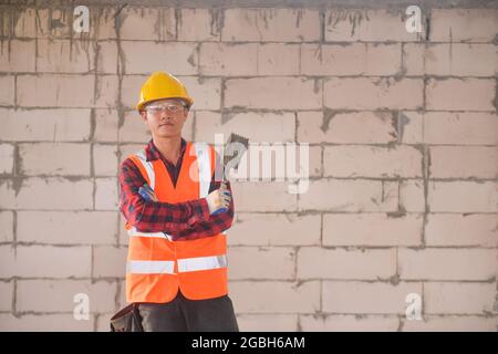 Porträt eines Maurerlayers, der auf einer Baustelle vor einer Wand steht Stockfoto