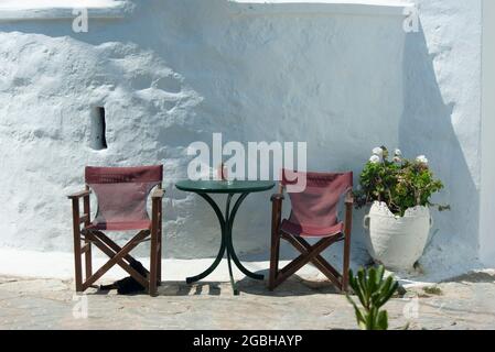 Griechenland - Insel Amorgos. Ein kleiner Platz mit Kapellen und Taverna-Tischen und -Stühlen Stockfoto