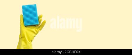 Hand in Schutzhandschuh mit blauem Schwamm auf beigem Hintergrund mit Kopierraum, Banner Stockfoto