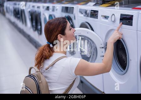 Kaukasische Frau wählt eine Waschmaschine in einem Haushaltswarenladen Stockfoto