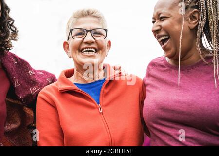 Multirassische ältere Frauen, die nach dem Sport-Workout im Freien Spaß zusammen haben - konzentrieren Sie sich auf das Gesicht der Frau in der Mitte Stockfoto