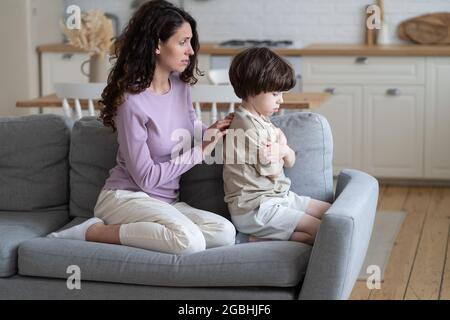 Entschuldigende Mutter versuchen, Frieden mit hartnäckigen beleidigten Jungen Kind Stirnrunzeln und ignorieren fürsorgliche Mutter zu machen Stockfoto