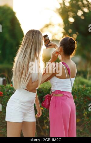 Portrait von zwei jungen Mädchen, die draußen Selfie auf dem Smartphone machen. Stockfoto