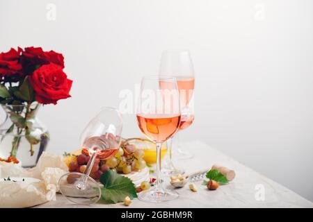 Roséwein und Sommergetränke rosa Cocktails mit Trauben auf dem festlichen Tisch, der bei einer Party mit Blumen geschmückt ist. Gruppe Gläser rosa Wein minimal Stockfoto