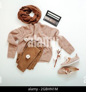 Mode Basic weibliche Kleidung Schuhe Set beige braune Farben gestrickt Pullover Schal und Baumwolle Blumen Kosmetik. Flach Lay Frühling Winter Frau weiblich Stockfoto