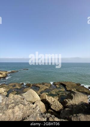 Blick auf die Küste, die im Sommer in Rabat, Marokko, Wasserzermalmen auf Felsen zeigt Stockfoto