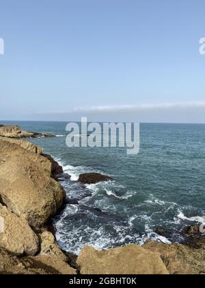 Blick auf die Küste, die im Sommer in Rabat, Marokko, Wasserzermalmen auf Felsen zeigt Stockfoto