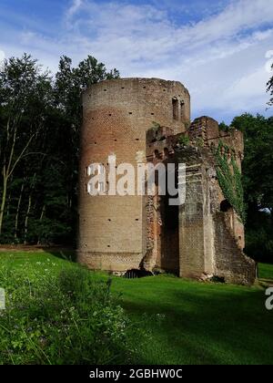 Eine Torheit (gefälschte Ruine) mit einem Efeu an den alten Wänden, Gras im Vordergrund und einem blauen Himmel mit Wolken Stockfoto