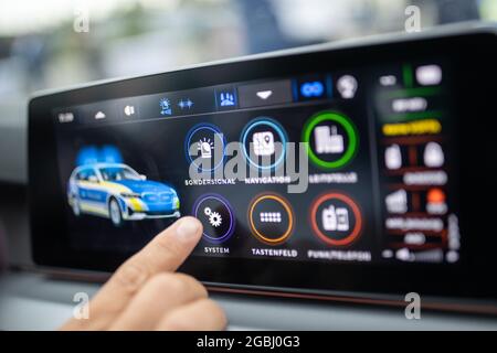 04. August 2021, Bayern, Nürnberg: Ein neues digitales Infotainment-System in einem Streifenwagen wird bei einer Demonstration auf der zentralen Steuereinheit demonstriert. Künftig wird das System bayerische Polizeibeamte in ihren Patrouillenwagen unterstützen, indem es sie beispielsweise automatisch an den Ort des Vorfalls führt. Radio, blinkendes blaues Licht, Sirene und Navigation können zentral am Steuergerät oder per App gesteuert werden. Foto: Daniel Karmann/dpa Stockfoto