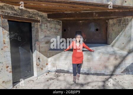 Walvisbunker in Burgh-Haamstede, Zeeland, Niederlande. 26. April 2021. Ältere Frau steht neben den Ruinen des verlassenen Bunkers aus dem Zweiten Weltkrieg, Teil Stockfoto