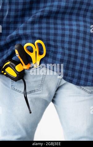 Reparaturkonzept. Maßband, Schraubendreher und Schere in der Jeanstasche, Nahaufnahme, Erntegut Stockfoto