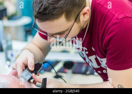 Der Meister schabt den Schnurrbart eines erwachsenen Mannes mit einer Schreibmaschine. Friseurservice-Konzept. Moskau, Russland 17. November 2016 Stockfoto