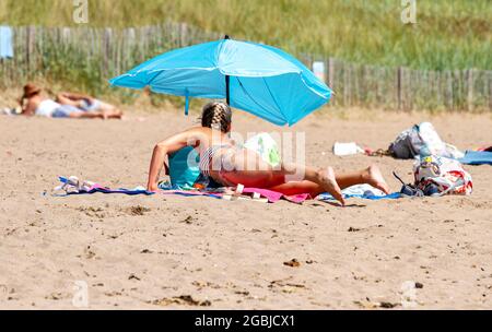 Dundee, Tayside, Schottland, Großbritannien. August 2021. UK Wetter: Heißer und sonniger Nachmittag in Dundee mit Temperaturen bis zu 21 Grad Sonnenanbeter genießen ihren Sommerurlaub im August und genießen den warmen, herrlichen Sonnenschein beim Sonnenbaden am Broughty Ferry Beach. Kredit: Dundee Photographics/Alamy Live Nachrichten Stockfoto