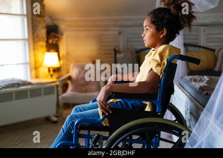 Schwarzes kleines Mädchen mit Behinderung im Rollstuhl zu Hause Stockfoto