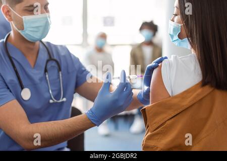 Asiatische Frau Erhält Coronavirus-Impfstoff-Injektion Sitzen Mit Arzt In Der Halle Stockfoto