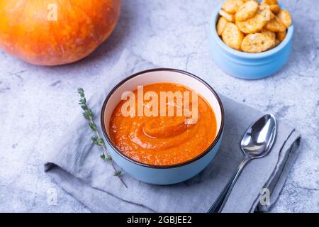 Kürbiscremesuppe mit Croutons und Thymian in einer Schüssel. Vegetarische, hausgemachte heiße Suppe. Grauer Hintergrund, Nahaufnahme. Stockfoto