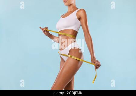 Nahaufnahme einer Frau, die den Körper mit Klebeband misst. Schlankheitskonzept Stockfoto