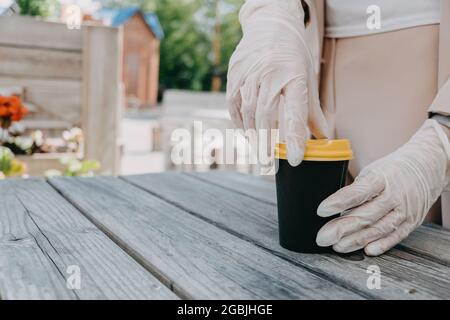 Lebensmittel- und Getränkeunternehmen während einer Coronavirus-Pandemie. Kaffee zum Mitnehmen Tasse in weiblichen Händen in Handschuhen. Restaurants, Pubs, Bars, Nachtclubs und Stockfoto
