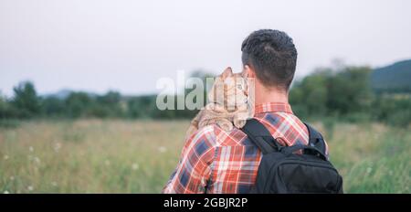 Katze sitzt auf der Schulter eines Mannes im Sommerpark. Stockfoto