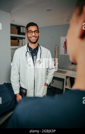 Mischling männliche Krankenschwester stehend lächelnd, während sie mit weiblicher Ärztin plaudert Stockfoto