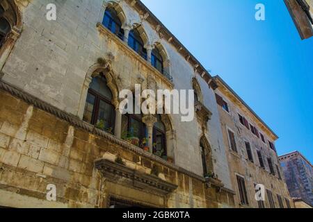 Ein altes gotisches Steinwohngebäude mit dreifachen Lanzettenfenstern in der historischen mittelalterlichen Küstenstadt Porec in Istrien, Kroatien Stockfoto