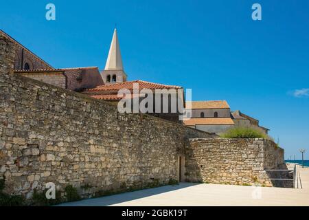 Teil der alten Verteidigungsmauern der historischen mittelalterlichen Küstenstadt Porec in Istrien, Kroatien. Der Glockenturm der Basilika kann man sehen Stockfoto