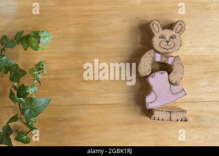 Holzkaninchen Puzzle-Spielzeug aus drei Teilen mit einem rosa Kleid auf einem hölzernen Hintergrund Stockfoto