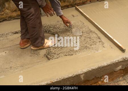 Indische Bauarbeiter verputzen Boden mit Kelle und Zement manuell, Bild Stock. Stockfoto