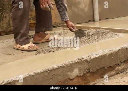 Indische Bauarbeiter verputzen Boden mit Kelle und Zement manuell, Bild Stock. Stockfoto