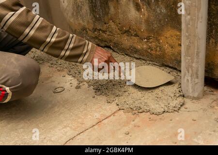 Indische Bauarbeiter verputzen Boden mit Kelle und Zement manuell, Bild Stock. Stockfoto
