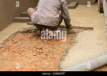 Indische Bauarbeiter verputzen Boden mit Kelle und Zement manuell, Bild Stock. Stockfoto