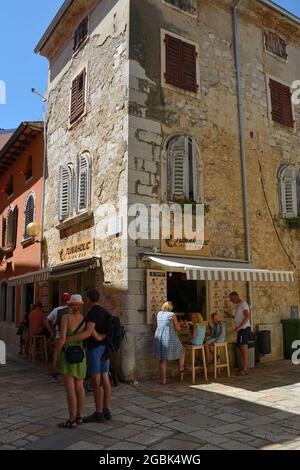 Porec, Kroatien - 10. Juli 2021. Touristen an einer Fischbar in der historischen mittelalterlichen Küstenstadt Porec in Istrien, Kroatien Stockfoto