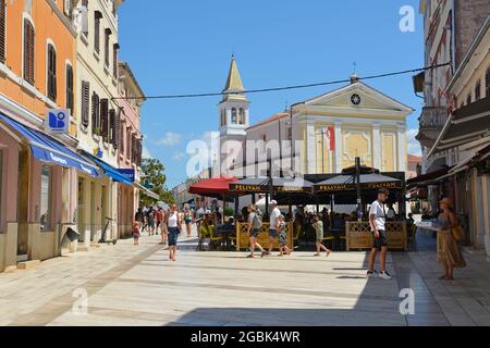 Porec, Kroatien - 10. Juli 2021. Eine Straße mit Geschäften, Banken, Restaurants und Touristen in der historischen mittelalterlichen Küstenstadt Porec in Istrien, C beschäftigt Stockfoto