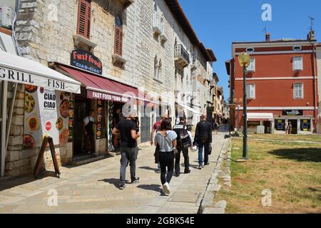 Porec, Kroatien - 10. Juli 2021. Eine Straße voller Geschäfte, Restaurants und Touristen in der historischen mittelalterlichen Küstenstadt Porec in Istrien, Kroatien Stockfoto