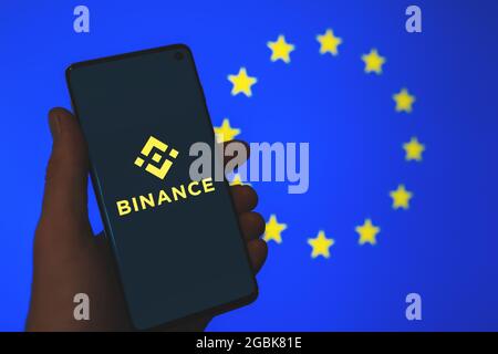 Binance App-Logo auf dem Smartphone in Verbindung mit dem verschwommenen Hintergrund der EU-Flagge. Binance in Europa, News zu EU-Vorschriften. Kryptoaustausch Stockfoto
