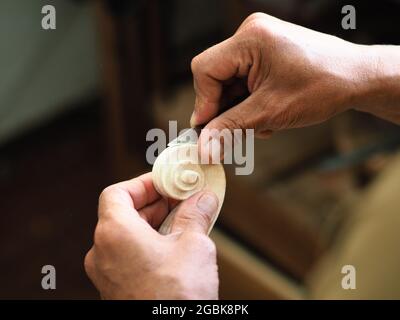 Geigenbauer, der an Geigenkopf und Locke arbeitet Stockfoto