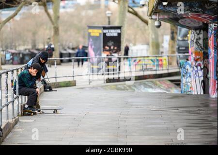 LONDON - 10. MÄRZ 2020: Freunde machen eine Pause vom Skateboarden in einem Skatepark am Südufer der Themse, London Stockfoto