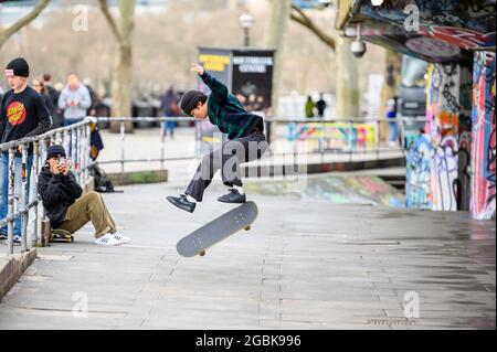 LONDON - 10. MÄRZ 2020: Skateboarder fotografiert mit dem Smartphone seinen Freund auf einem Skateboard im Skatepark am Londoner Themse South Bank Stockfoto