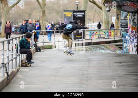 LONDON - 10. MÄRZ 2020: Der junge Skateboarder übt seine Moves mit einem Freund im Skate Center an der Londoner South Bank Stockfoto