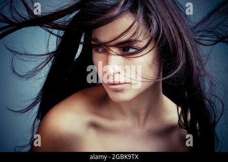Junge Frau mit dunklem Haar in Bewegung Porträt, Studio-Aufnahme Stockfoto