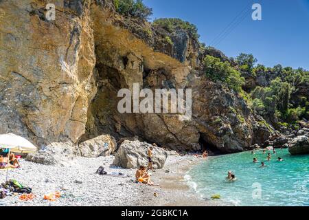 Panoramablick auf Foneas Strand überfüllt mit Touristen und Schwimmern. Der felsige Strand befindet sich in der Küstenregion Mani in der Nähe des Dorfes Kardamyli in M Stockfoto