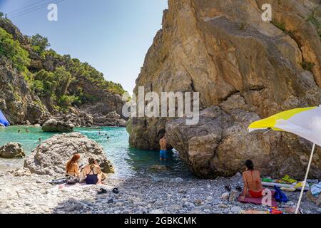 Panoramablick auf Foneas Strand überfüllt mit Touristen und Schwimmern. Der felsige Strand befindet sich in der Küstenregion Mani in der Nähe des Dorfes Kardamyli in M Stockfoto