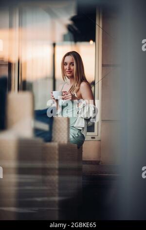 Entzückende kaukasische Frau sitzt und Frühstück mit einer Tasse Kaffee Stockfoto