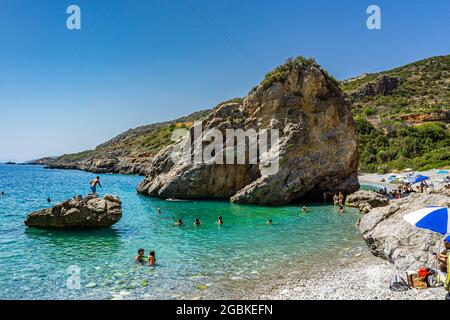 Panoramablick auf Foneas Strand überfüllt mit Touristen und Schwimmern. Der felsige Strand befindet sich in der Küstenregion Mani in der Nähe des Dorfes Kardamyli in M Stockfoto